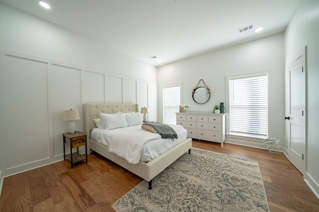 bedroom featuring recessed lighting, wood finished floors, visible vents, and a decorative wall