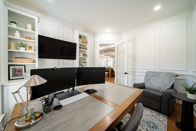 office with ornamental molding, built in shelves, light wood-style floors, and a decorative wall