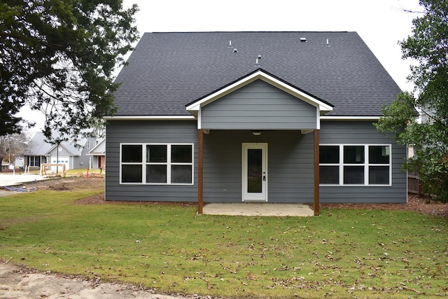 back of property featuring a yard, a shingled roof, and a patio area