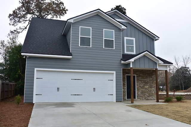 view of front of home featuring a garage, a shingled roof, concrete driveway, stone siding, and board and batten siding