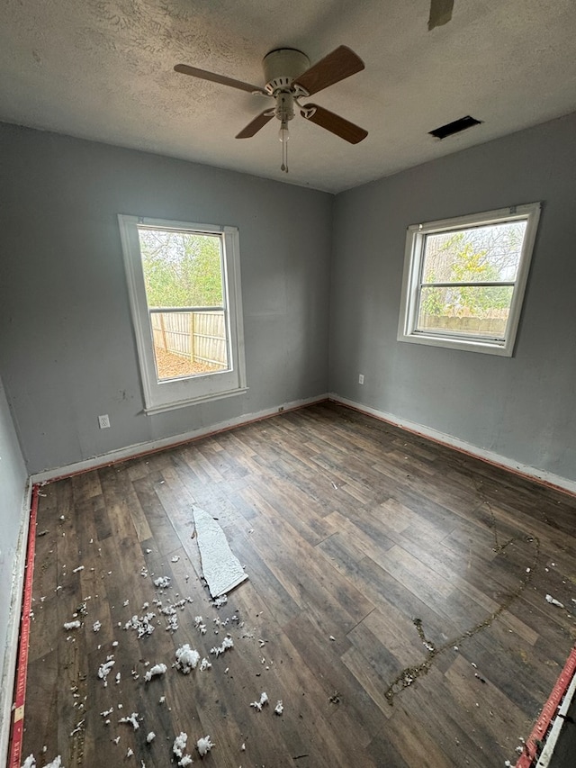 spare room with wood-type flooring, a healthy amount of sunlight, and baseboards