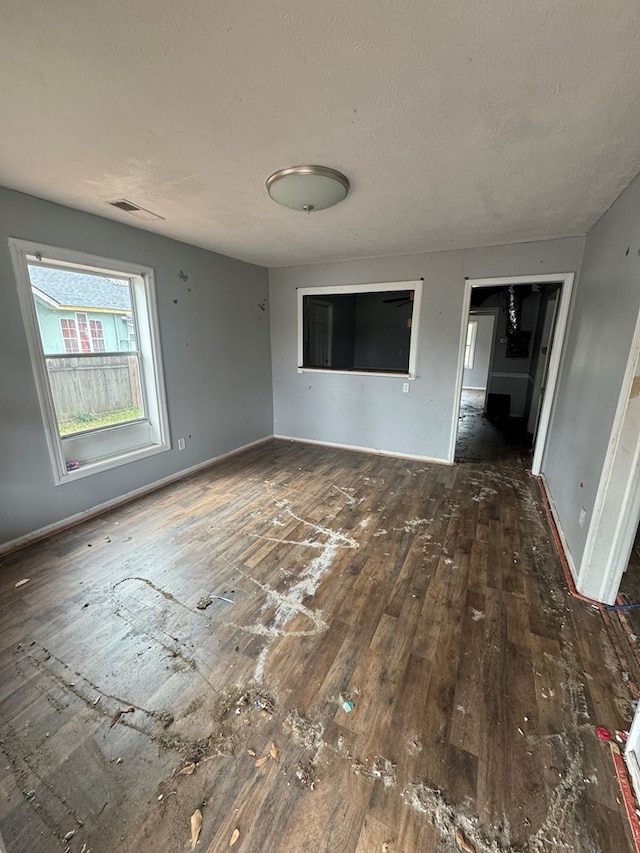 spare room featuring baseboards, a textured ceiling, visible vents, and hardwood / wood-style floors