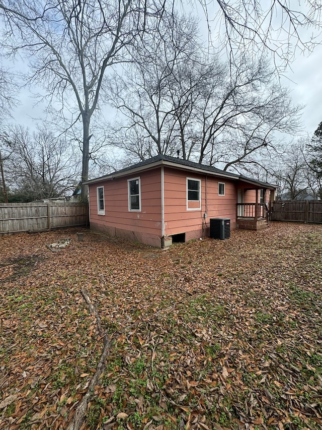 view of side of home with central AC unit and fence private yard