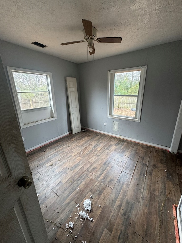 unfurnished bedroom with baseboards, visible vents, a ceiling fan, hardwood / wood-style floors, and a textured ceiling