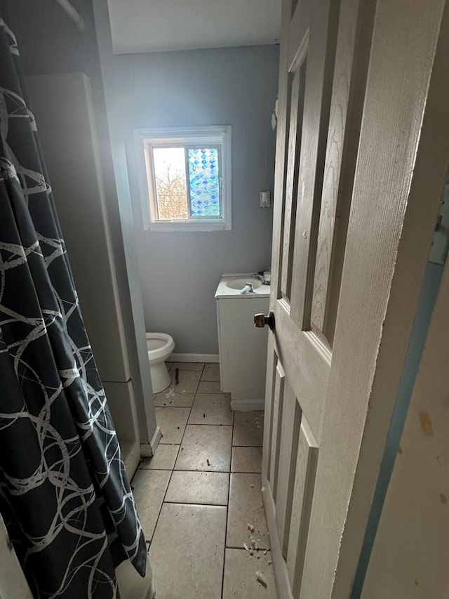 bathroom with curtained shower, vanity, toilet, and baseboards