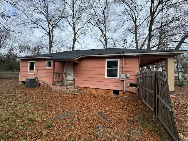 view of front of house with a shingled roof, fence, and central air condition unit