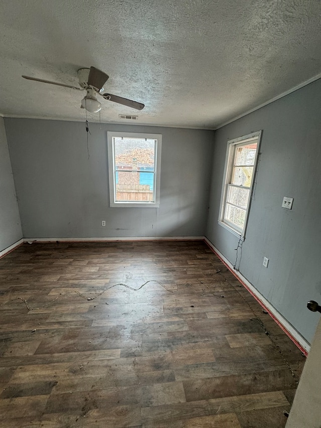 spare room featuring baseboards, visible vents, dark wood finished floors, ceiling fan, and a textured ceiling