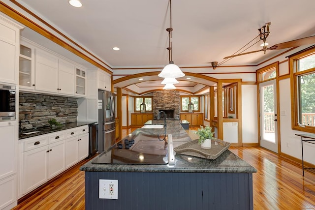 9250-11 River Rd, Fortson, GA 31808 - kitchen featuring stainless steel appliances, a stone fireplace, white cabinets, light wood-style flooring, and decorative backsplash