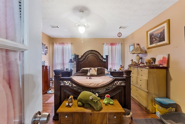 bedroom featuring dark hardwood / wood-style flooring, ceiling fan, and a textured ceiling