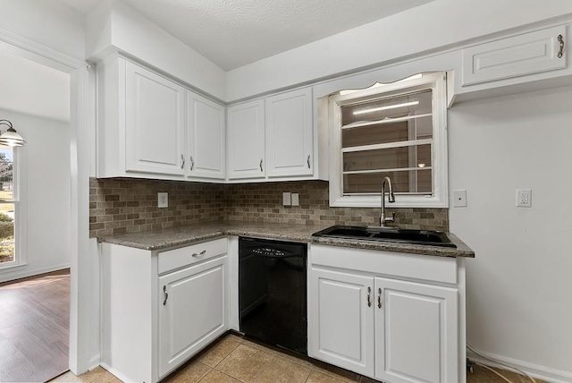 kitchen with sink, white cabinetry, tasteful backsplash, dishwasher, and dark stone counters