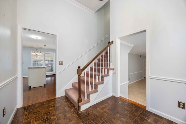 stairway featuring ornamental molding, a notable chandelier, and baseboards