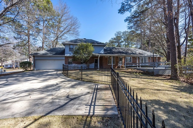 view of front of house with an attached garage, driveway, a fenced front yard, and brick siding