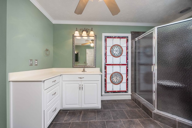 bathroom featuring a stall shower, ceiling fan, vanity, a textured ceiling, and crown molding