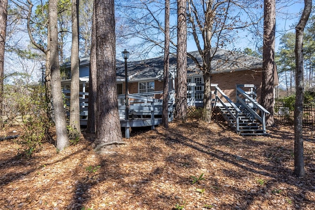 back of house with brick siding, stairway, a wooden deck, and fence