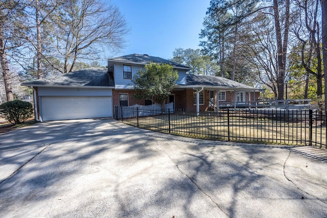 view of front of house with driveway, brick siding, a fenced front yard, and an attached garage