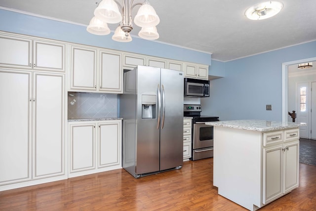 kitchen with appliances with stainless steel finishes, a center island, backsplash, and wood finished floors