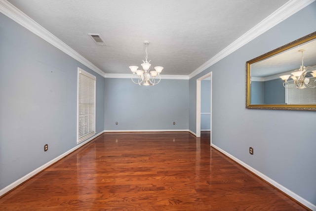 spare room with ornamental molding, visible vents, a notable chandelier, and wood finished floors