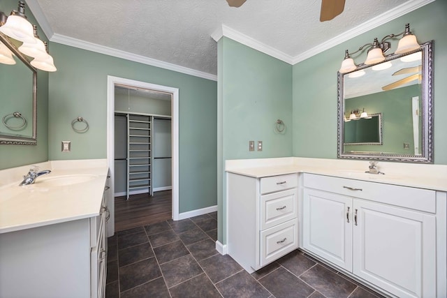 full bath with a textured ceiling, a ceiling fan, two vanities, and a sink