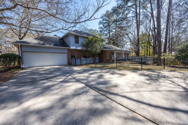 view of front of home featuring driveway, a fenced front yard, an attached garage, and brick siding