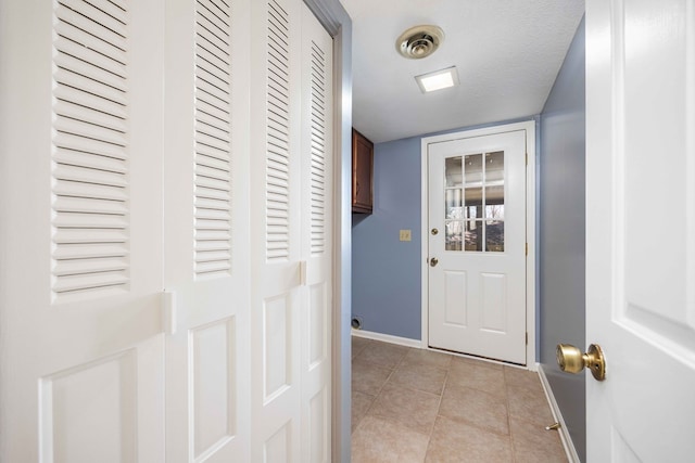 doorway to outside featuring visible vents, a textured ceiling, baseboards, and light tile patterned flooring