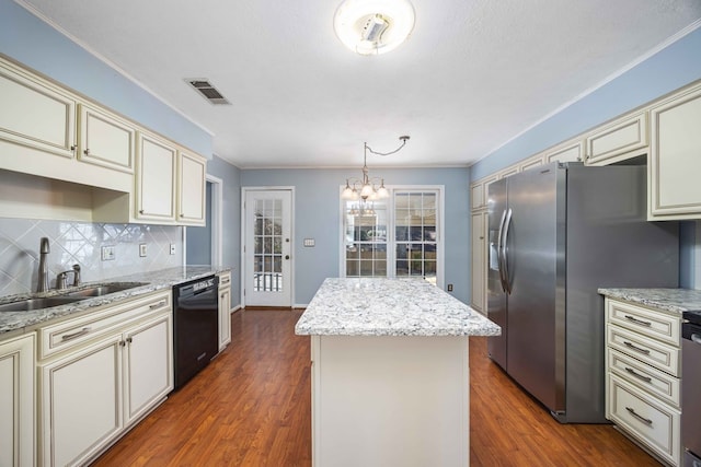 kitchen featuring cream cabinets, a sink, visible vents, black dishwasher, and stainless steel fridge