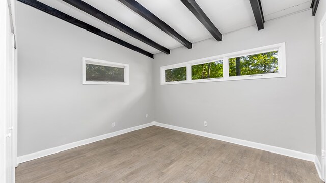 spare room featuring vaulted ceiling with beams and hardwood / wood-style flooring