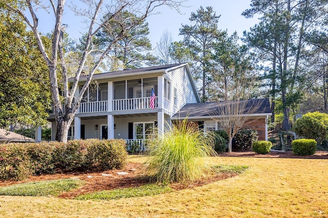 view of front facade featuring a front yard, brick siding, and a sunroom