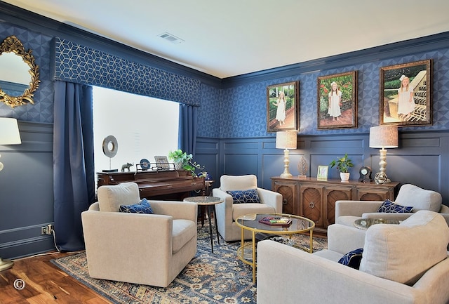 living area featuring wallpapered walls, visible vents, dark wood finished floors, wainscoting, and a decorative wall