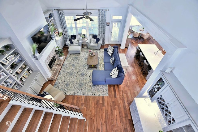 living area with ceiling fan, built in features, and wood finished floors