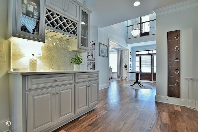 bar with baseboards, backsplash, dark wood-style floors, a dry bar, and crown molding