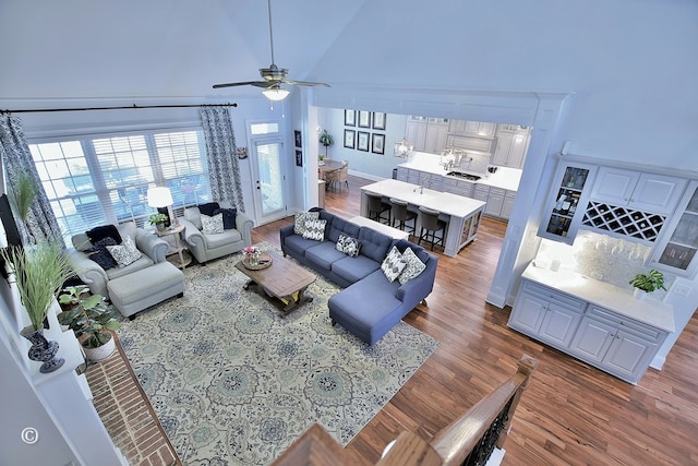 living room featuring a towering ceiling, dark wood-style floors, and ceiling fan