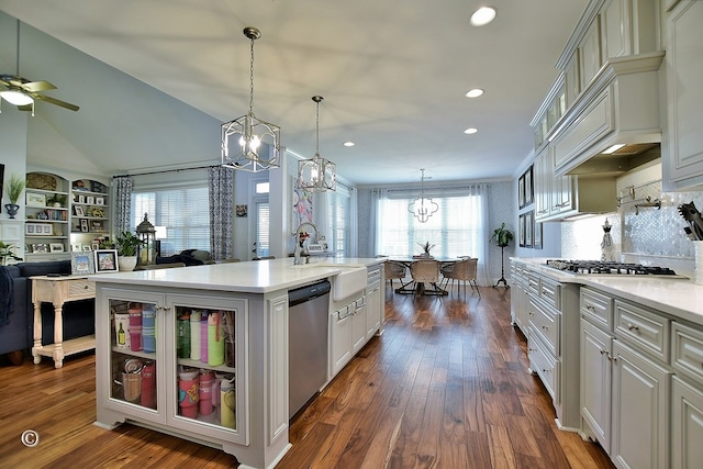 kitchen featuring a kitchen island with sink, a sink, light countertops, appliances with stainless steel finishes, and glass insert cabinets