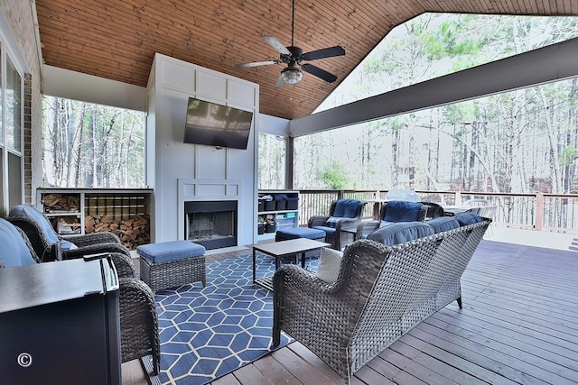 wooden terrace with ceiling fan and an outdoor living space with a fireplace