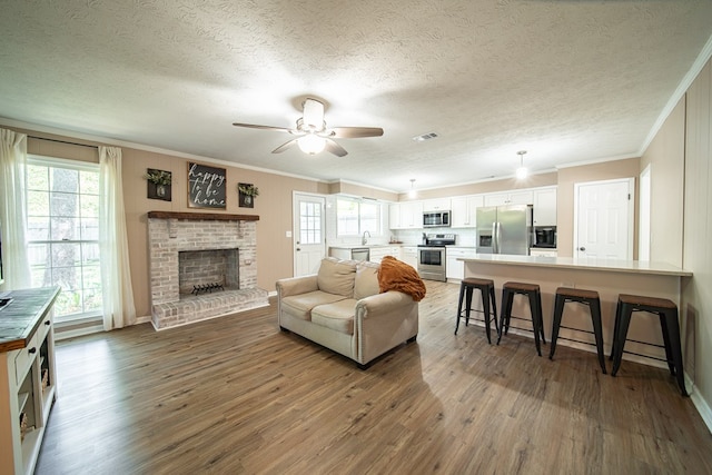 6801 Buckeye Way, Columbus, GA 31904 - living area featuring wood finished floors, crown molding, a ceiling fan, a fireplace, and a textured ceiling