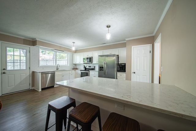 6801 Buckeye Way, Columbus, GA 31904 - kitchen with stainless steel appliances, a peninsula, dark wood-type flooring, a kitchen breakfast bar, and light stone counters