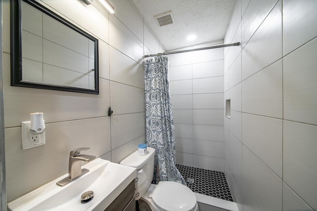 bathroom with vanity, a textured ceiling, a shower with shower curtain, and tile walls