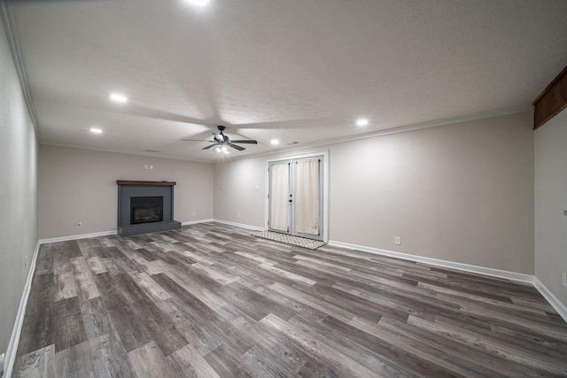 unfurnished living room with ornamental molding, a textured ceiling, ceiling fan, dark wood-type flooring, and a fireplace