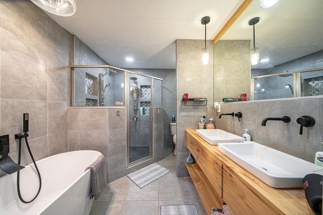 full bathroom featuring tile patterned floors, vanity, toilet, and tile walls