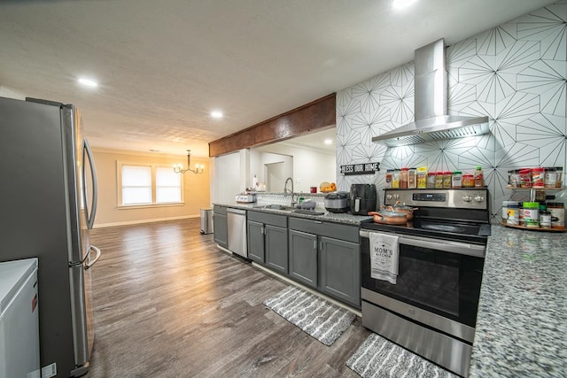 kitchen with wall chimney range hood, sink, gray cabinets, a notable chandelier, and stainless steel appliances