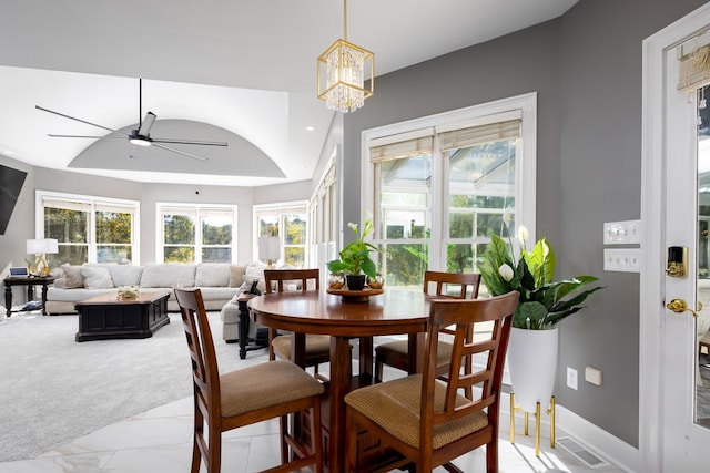 dining room featuring light colored carpet and ceiling fan with notable chandelier