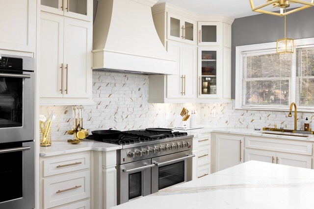 5410 River Oak Way, Phenix City, AL 36867 - kitchen featuring custom exhaust hood, appliances with stainless steel finishes, a sink, tasteful backsplash, and white cabinetry