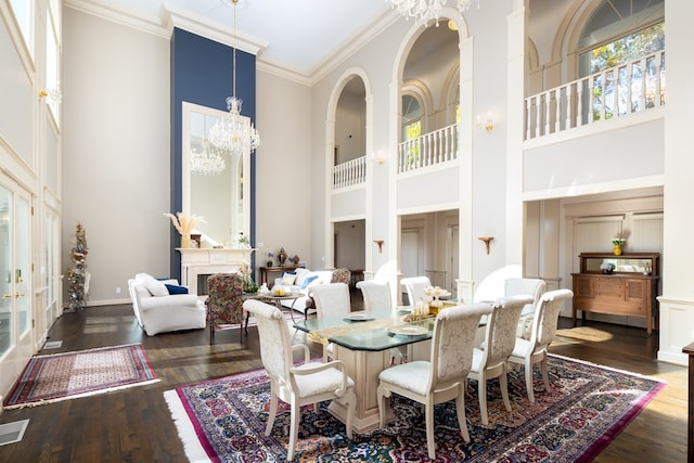 dining room with dark hardwood / wood-style flooring, a towering ceiling, crown molding, and an inviting chandelier