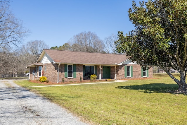 ranch-style house with brick siding, driveway, a shingled roof, and a front lawn