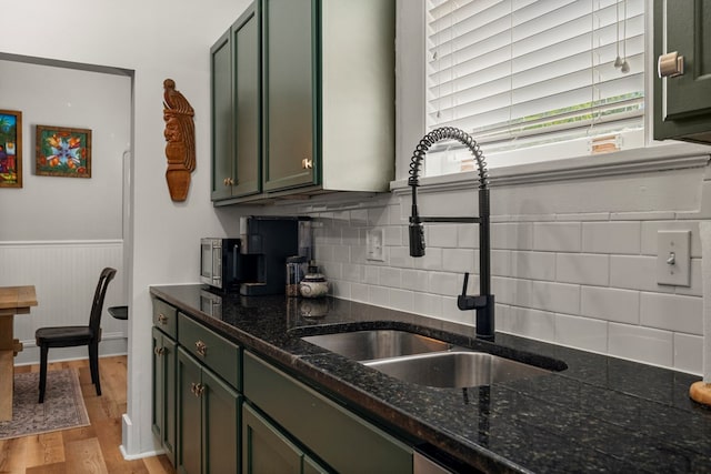1917 Dimon St, Columbus, GA 31906 - kitchen with light wood-type flooring, wainscoting, dark stone countertops, green cabinetry, and backsplash