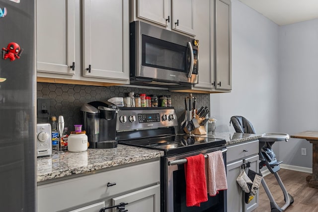 28 Red Maple Dr, Phenix City, AL 36869 - kitchen with backsplash, appliances with stainless steel finishes, wood finished floors, light stone counters, and baseboards