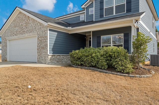 view of front of home featuring a garage, a front yard, and central air condition unit