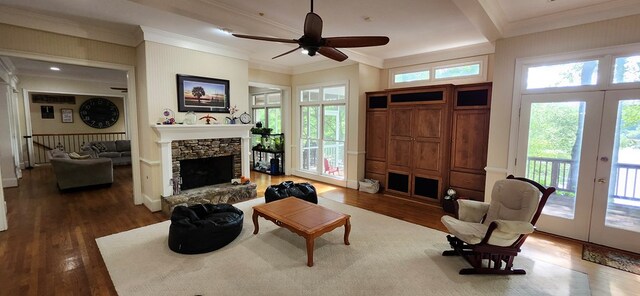 living area with ceiling fan, french doors, a fireplace, wood finished floors, and ornamental molding