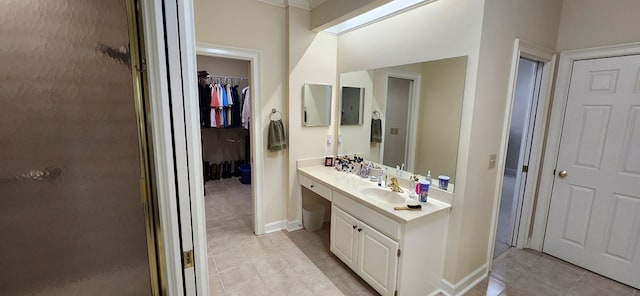 full bathroom with a walk in closet, tile patterned flooring, vanity, baseboards, and a stall shower