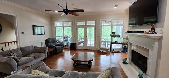 living room featuring a high end fireplace, ceiling fan, wood finished floors, and ornamental molding