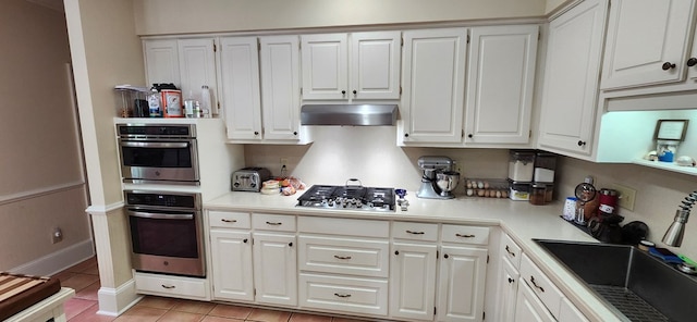 kitchen with extractor fan, light countertops, white cabinets, a sink, and stainless steel appliances
